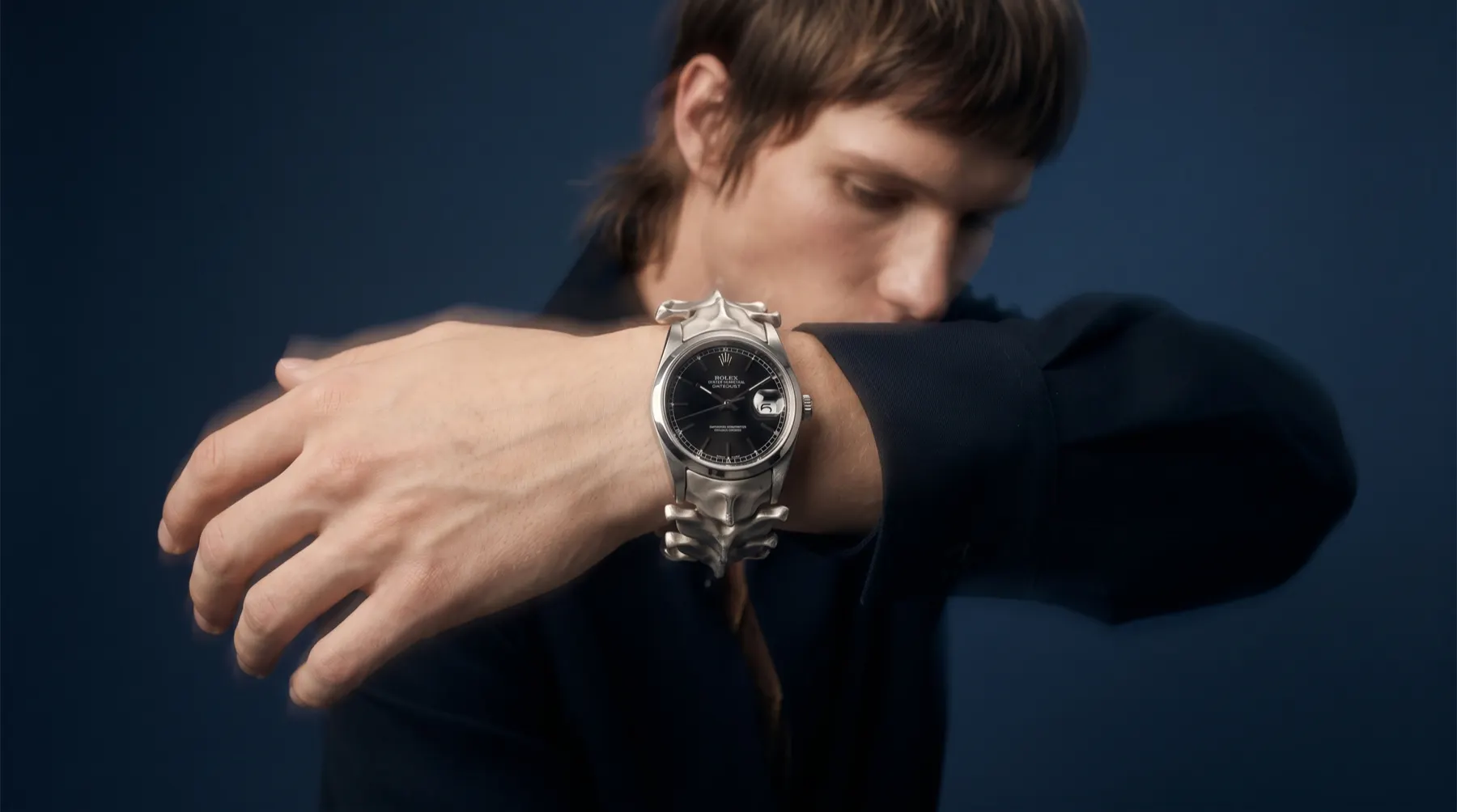 Watch emerging from darkness with liquid metal splash